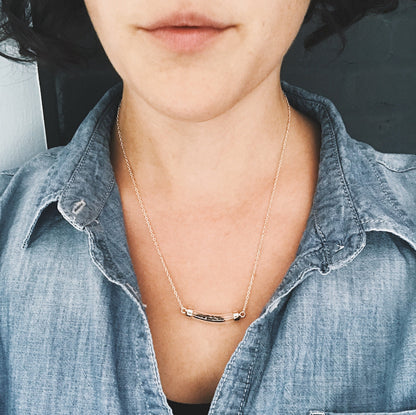 Wiman wearing a necklace with meteorite stardust with a minimalistic design, wearing a denim shirt.