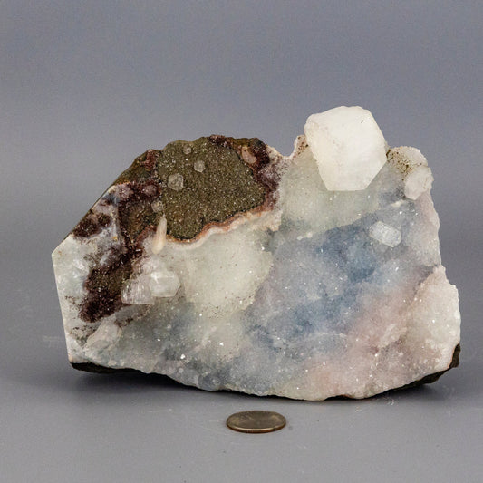 Chalcedony quartz cluster with a coin for scale on a gray background