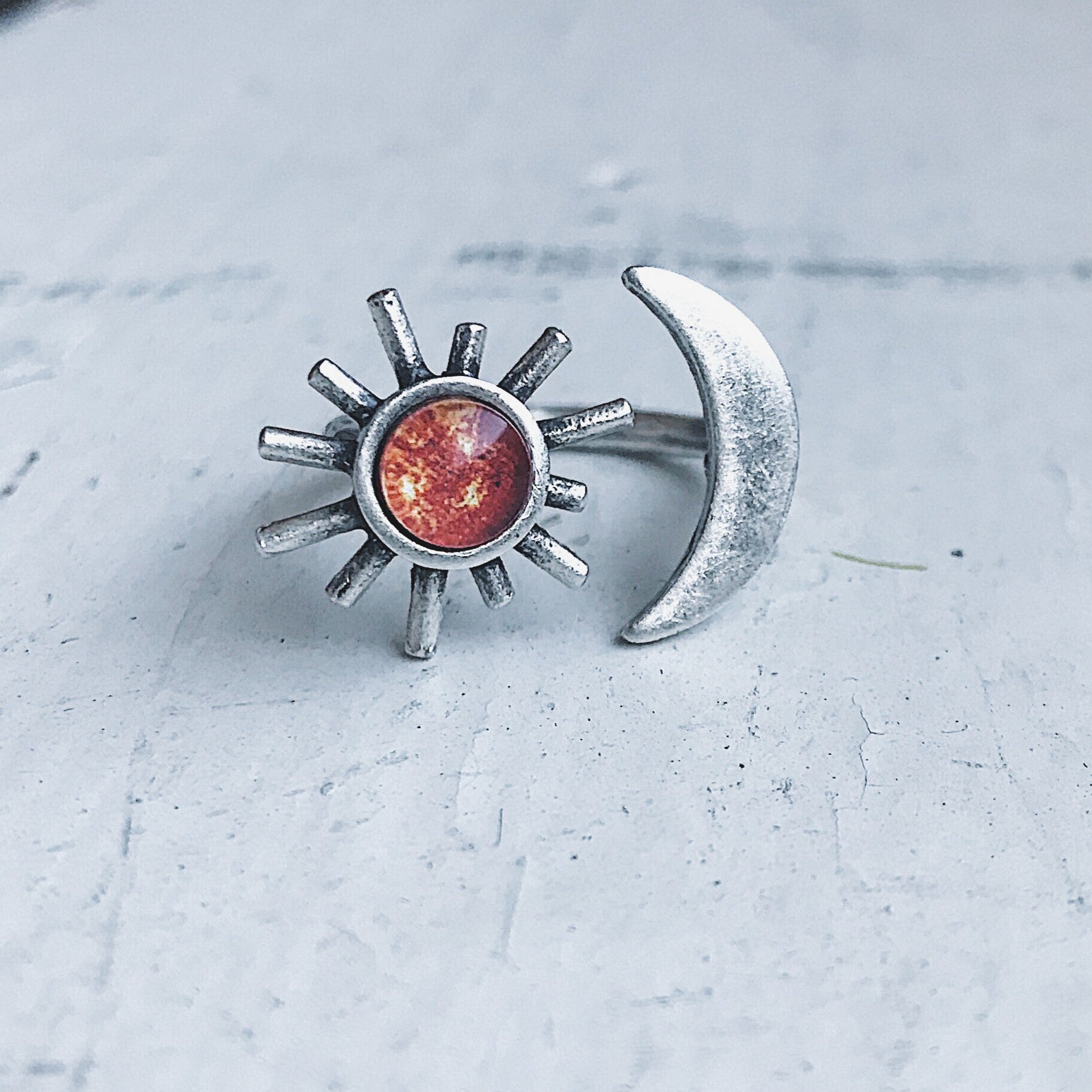 Silver sun and moon ring on a light gray surface