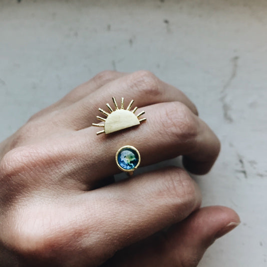 Hand wearing a ring with a sun design and with a gemstone.