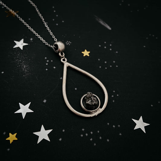 Teardrop-shaped pendant necklace with star decorations on a dark background