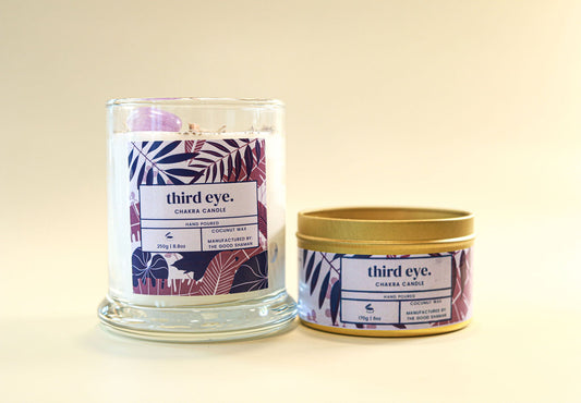 Two 'third eye.' candles, one in a glass jar and one in a tin, on a beige background.
