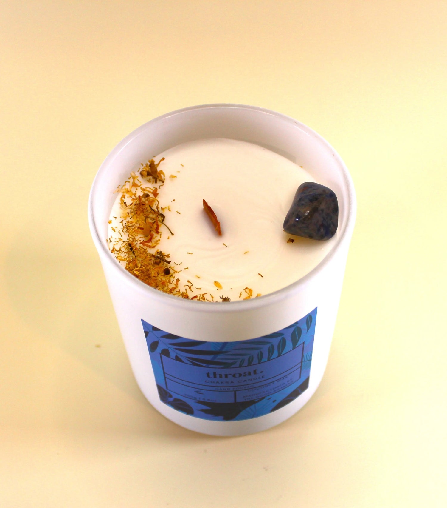 Candle in a white container with decorative elements on a yellow background