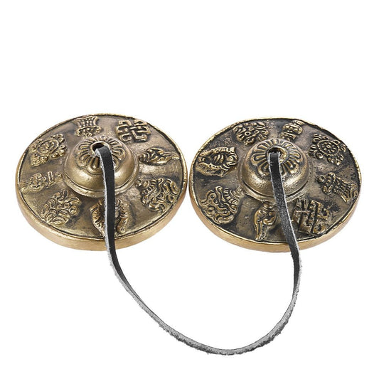 Pair of bronze hand chimes with intricate designs on a white background