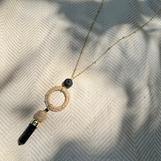 Black agate necklace with black crystal pendant on a textured fabric background