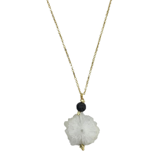 Necklace with a white floral pendant and black bead on a gold chain against a white background