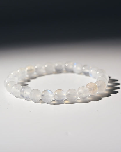 Moonstone beaded bracelet on a reflective surface with a dark background
