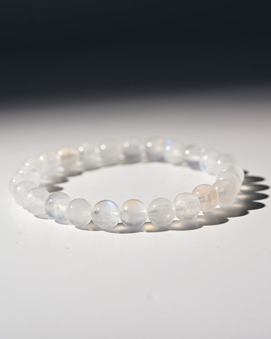 Moonstone beaded bracelet on a reflective surface with a dark background